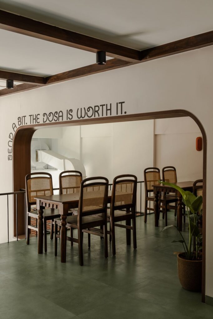 The upstairs dining room at Benne & Brew with cane chairs and the wall line Bend a bit, the dosa is worth it