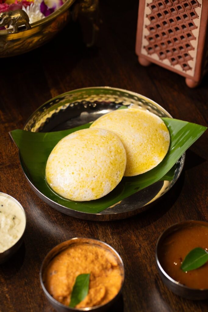 Two butter-glazed idlis on a banana leaf