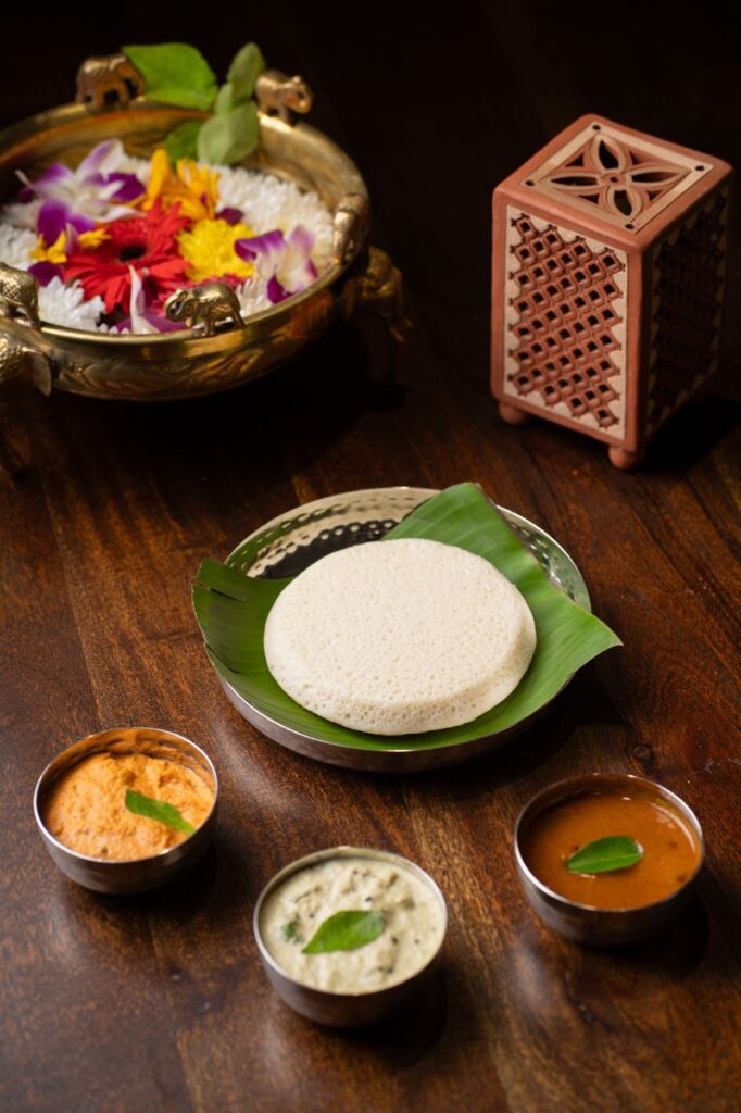 A single large, flat thatte idli on a banana leaf