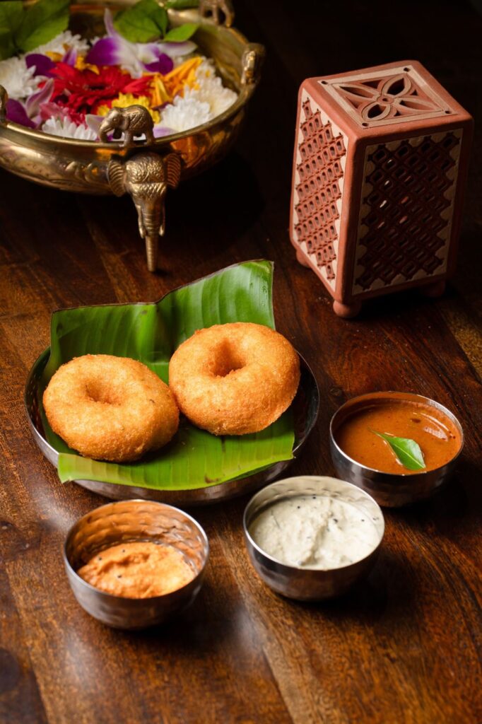 Two golden medu vadas on a banana leaf