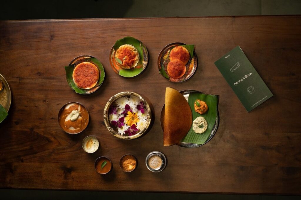 Overhead view of a table spread with dosa, idlis, vadas, chutneys and the Benne & Brew menu