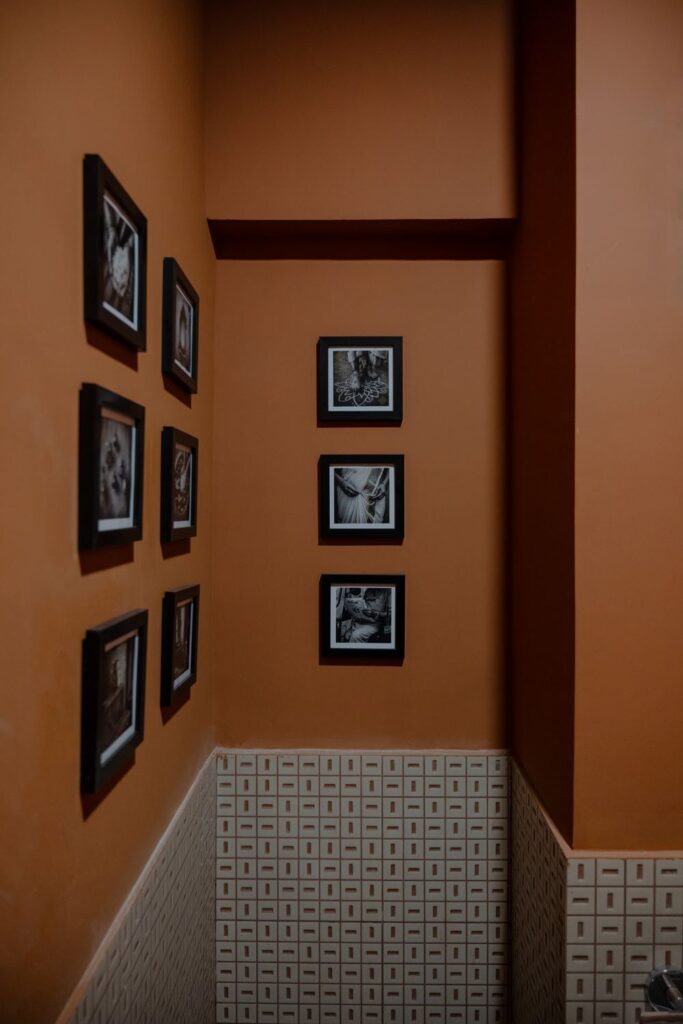 Framed black-and-white photographs on the terracotta wall at Benne & Brew above patterned cream tiles