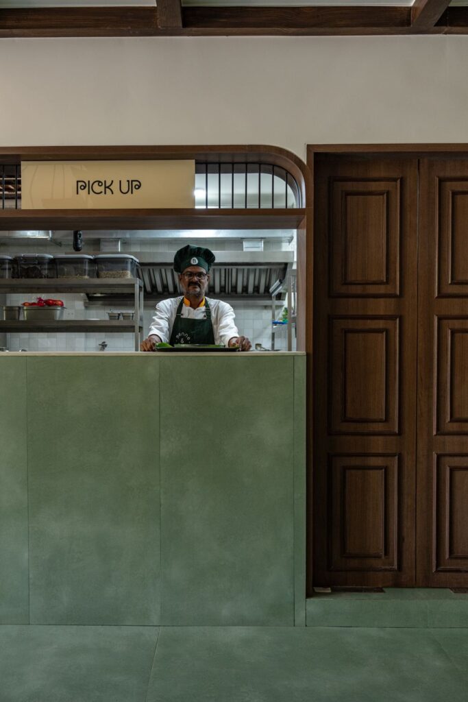 A chef at the Pick Up window of the open kitchen at Benne & Brew, Viman Nagar