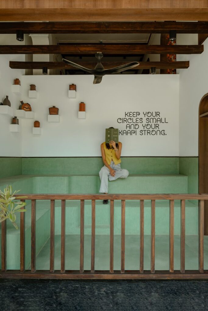 The Verandah seating area at Benne & Brew, with mint-green bench steps under the wall lettering Keep your circles small and your kaapi strong