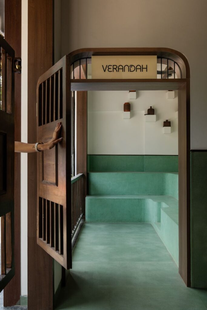 The wooden Verandah door held open at Benne & Brew, Viman Nagar, showing the mint-green bench seating beyond